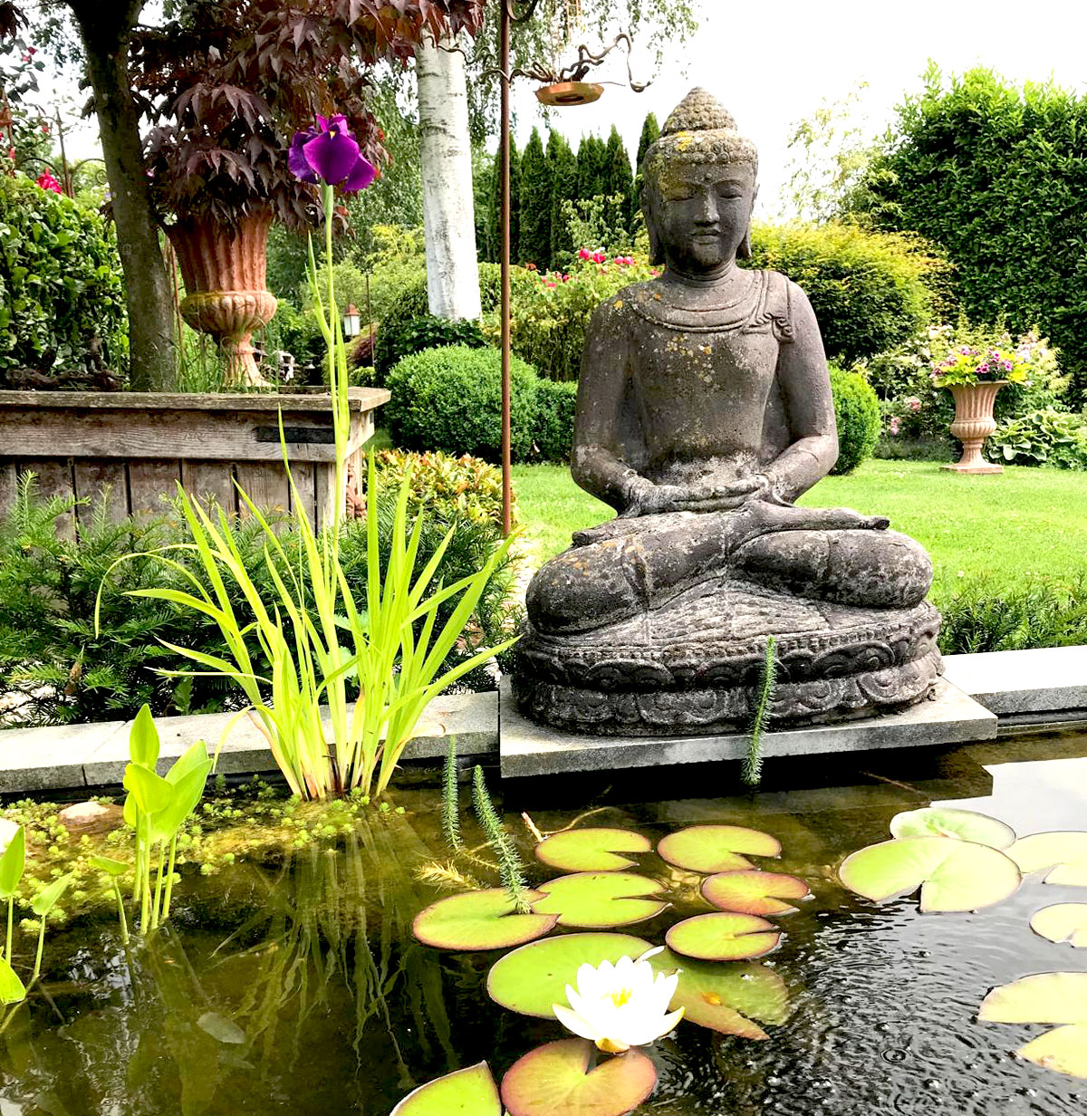 Steinerne Buddha-Figur vor Gartenteich